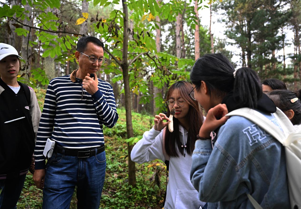 王占斌老師給同學(xué)們講解辨識蘑菇。（學(xué)校供圖）.jpg