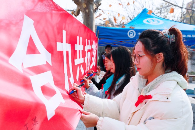 20231127中國石油大學(xué)（華東）青年學(xué)子在合力共抗艾滋的條幅上簽字，表達(dá)抗擊艾滋病的決心和信心  .jpg